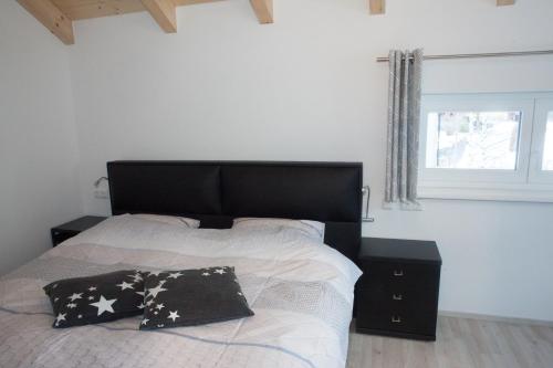a bedroom with a black and white bed and a window at Ferienhäuser Glück Auf, Sauna, Hottubs in Arnoldstein