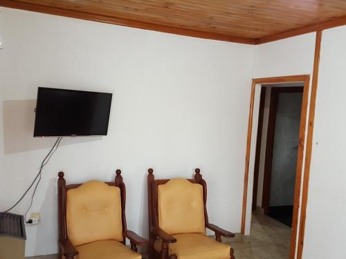 two chairs in a room with a tv on a wall at Cabañas Años Verdes in Sarmiento