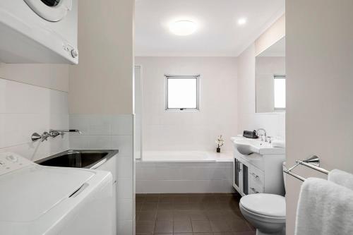 Baño blanco con lavabo y aseo en Quest Wollongong, en Wollongong