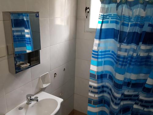 a bathroom with a sink and a shower curtain at Cabañas Años Verdes in Sarmiento