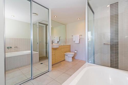 a bathroom with a tub and a toilet and a shower at Peppers Blue on Blue in Nelly Bay
