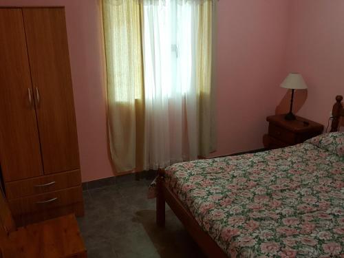 a bedroom with a bed and a dresser and a window at Cabañas Años Verdes in Sarmiento