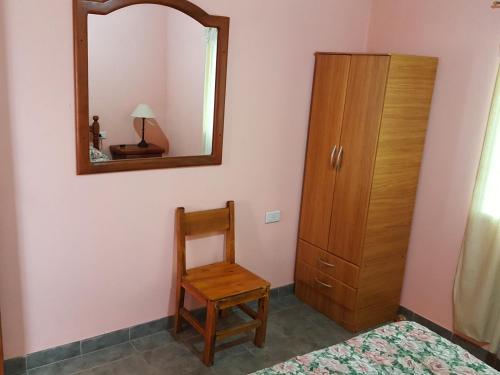 a bedroom with a mirror and a chair and a dresser at Cabañas Años Verdes in Sarmiento