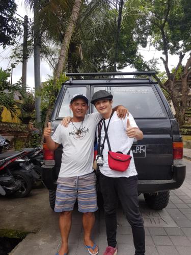 two men are standing in front of a car at Black Lava Hostel and Lodge in Kintamani