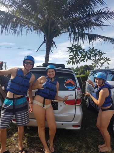 three women in bathing suits standing in front of a car at Black Lava Hostel and Lodge in Kintamani