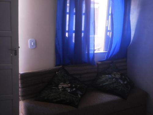 un sofá en una habitación con una ventana con cortinas azules en Casa, en Cabo Frío