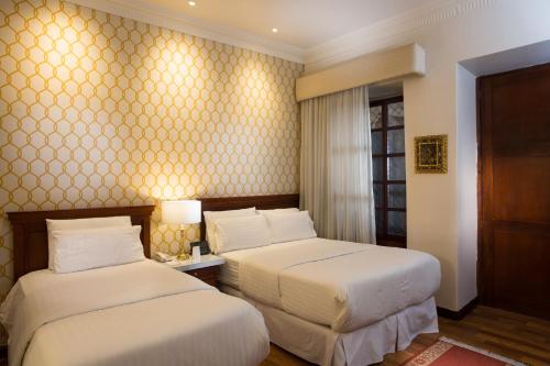 a hotel room with two beds and a window at Hotel Boutique Santa Lucia in Cuenca