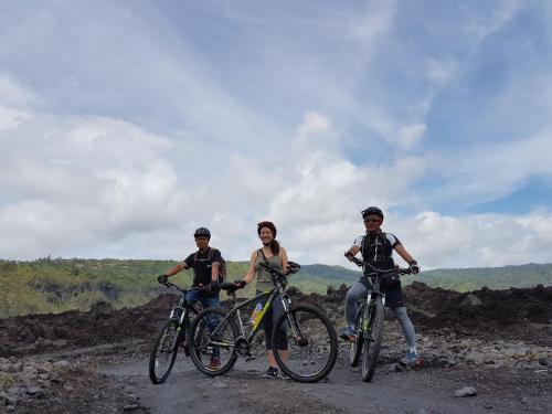 three people standing with their bikes on a dirt road at Black Lava Hostel and Lodge in Kintamani