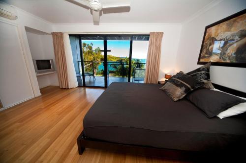 1 dormitorio con 1 cama negra grande y balcón en Shorelines 2 on Hamilton Island by HamoRent en Isla Hamilton