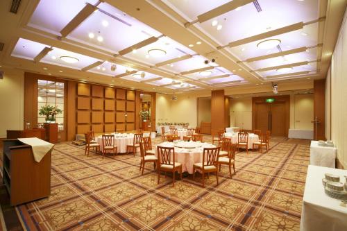 a banquet hall with white tables and chairs at HOTEL MYSTAYS PREMIER Narita in Narita
