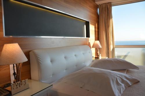 a bedroom with a white bed and a large window at Scorpios Sea Side Hotel in Piraeus
