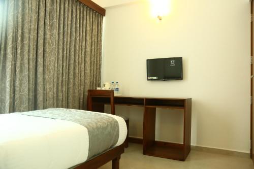 a bedroom with a bed and a tv on the wall at Niko Hotels in Cochin
