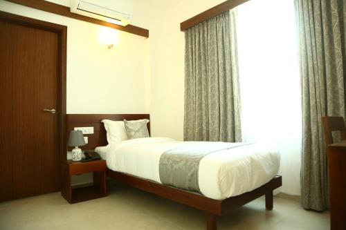 a bedroom with a bed and a window at Niko Hotels in Cochin