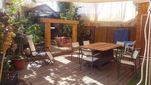 una terraza de madera con mesa y sillas de madera en Casa Rosa, en Eilat