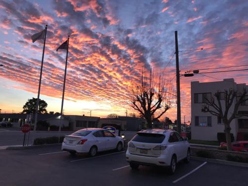 two cars parked in a parking lot with a sunset at Howard Johnson by Wyndham Salinas in Salinas