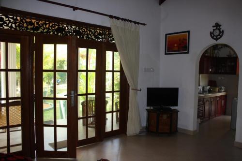 a living room with doors open to a kitchen with a television at Aliya Lanka in Beruwala