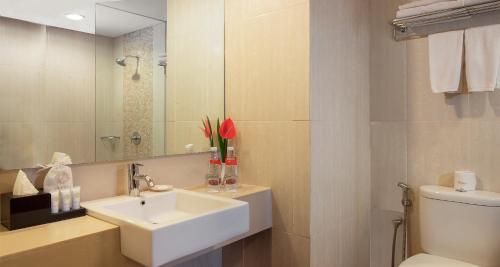 a bathroom with a sink and a toilet and a mirror at Atria Hotel Magelang in Magelang