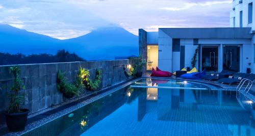 a swimming pool with a view of mountains at night at Atria Hotel Magelang in Magelang