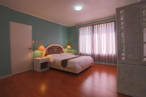 a bedroom with a bed and a large window at Beach Garden Hotel in Saipan