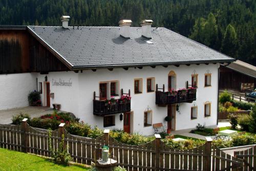 a white house with balconies and a fence at Landhaus Strickenmacher in Sillian