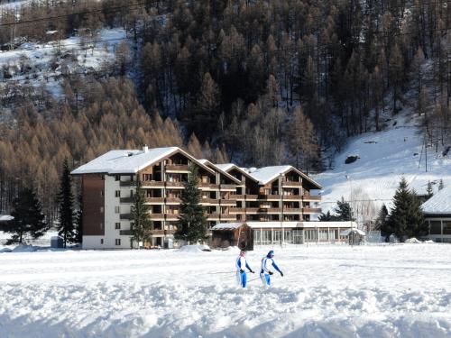 two people walking in the snow in front of a lodge at Cosy 3.5 pièce à Täsch in Täsch