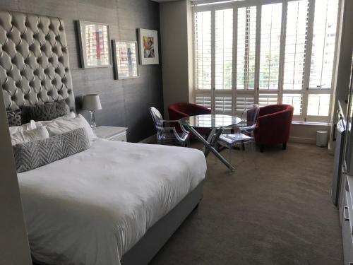 a bedroom with a bed and a table and chairs at Sandton Skye in Johannesburg