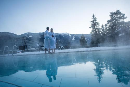 two people standing next to a swimming pool at Hotel Waldhof in Perca