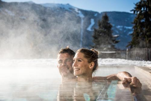 a man and a woman swimming in a hot tub at Hotel Waldhof in Perca