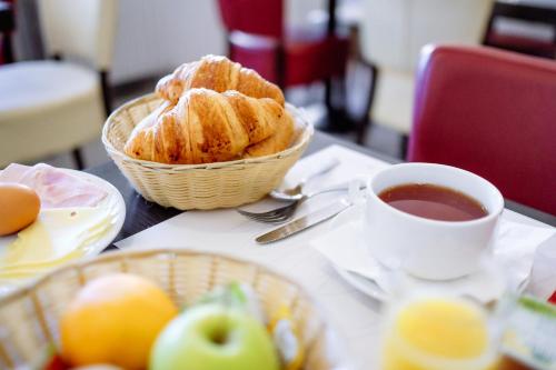 - une table avec un panier de pain et une tasse de thé dans l'établissement Hôtel Restaurant du Lauragais LOGIS DE FRANCE, à Villefranche-de-Lauragais