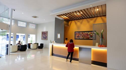 Eine Frau, die an einem Tresen in einer Lobby steht. in der Unterkunft Hotel Quirin in Semarang