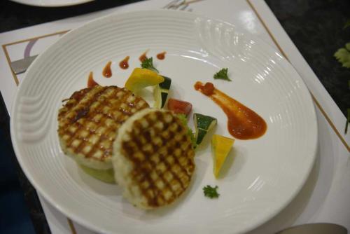 a white plate with a sandwich and corn dogs on it at Pride Hotel & Convention Centre Indore in Indore