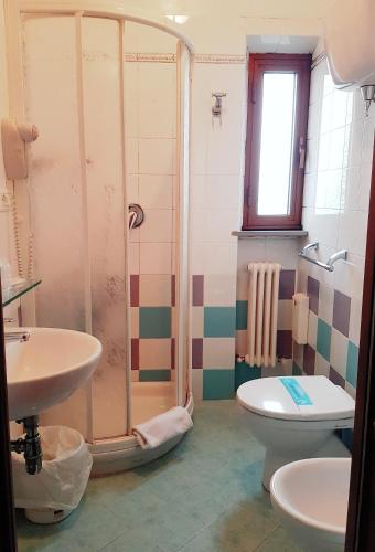a bathroom with a shower and a toilet and a sink at Hotel Porta Romana di Luce Hotels in Siena