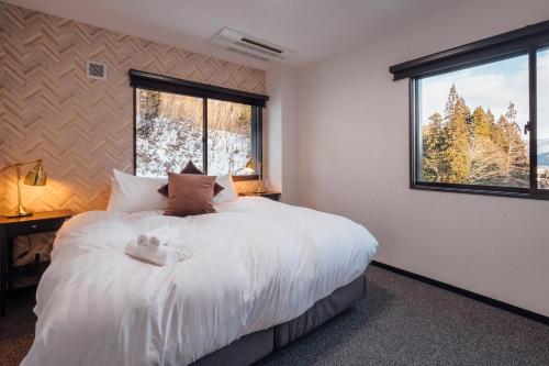 a bedroom with a bed with two teddy bears on it at Happo Apartments by HHG in Hakuba