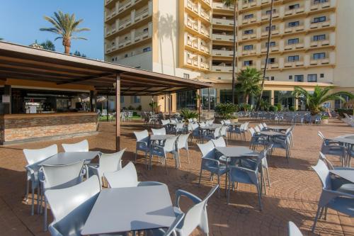 an outdoor patio with tables and chairs in front of a building at BLUESEA Costa Serena in Torremolinos