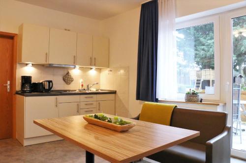 a kitchen and a table with a bowl of fruit on it at GRÜNBLAU RELAX Pension & Apartments in Warnemünde