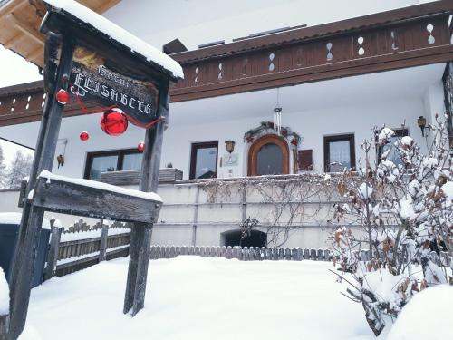 a house covered in snow with a sign in front at Haus Elisabeth in Nova Ponente