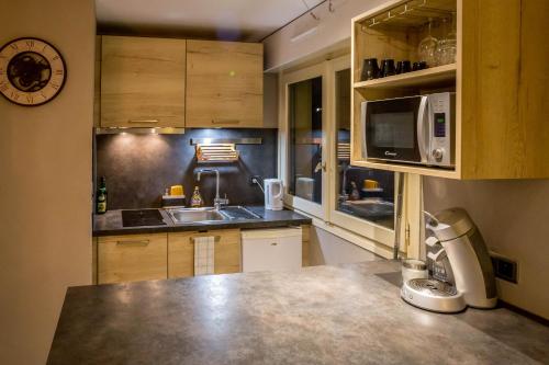une cuisine avec un évier et un micro-ondes dans l'établissement Studio Belmont - Centre village la Clusaz - AravisTour, à La Clusaz