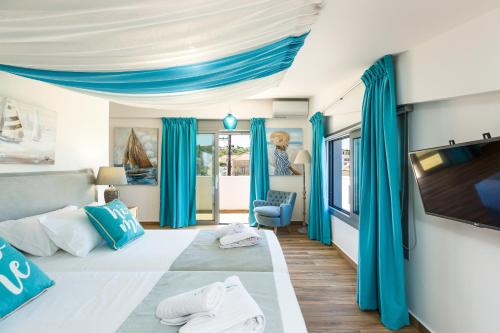a bedroom with blue curtains and a flat screen tv at Contessa Del Mare in Panormos Rethymno