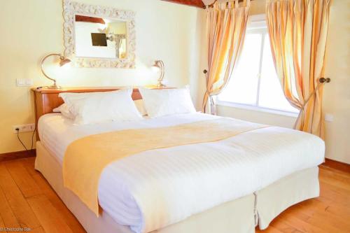 a bedroom with a large white bed with a mirror at Les Jardins d'Epicure in Bray-et-Lû