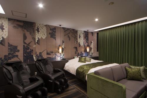 a bedroom with a bed and two chairs and a couch at WA HOTEL TIMELESS RESORT - Adult Only in Wakayama