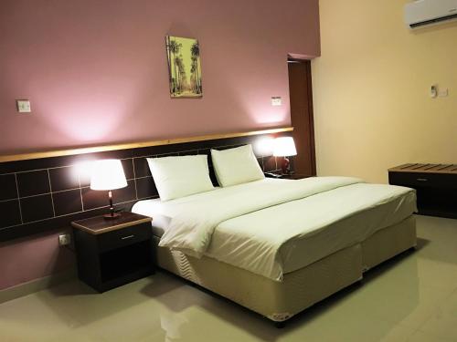 a bedroom with a large bed with two lamps at Mutrah Hotel in Muscat