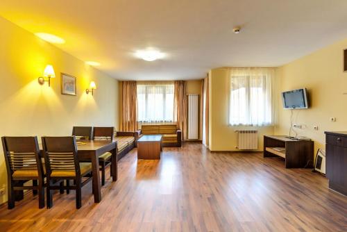 sala de estar con mesa, sillas y TV en Apart Hotel Dream en Bansko