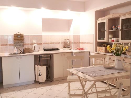 シフィノウイシチェにあるApartamenty MARINEのキッチン(白いキャビネット、テーブル、椅子付)