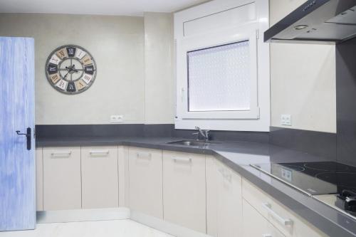 uma cozinha com armários brancos e um relógio na parede em Ancora em Tamariu
