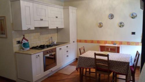 a kitchen with white cabinets and a table with chairs at Dentro le mura in Rieti