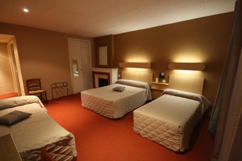 a hotel room with two beds and a table at Logis Hotel L'ange Couronne in Belleville-sur-Saône