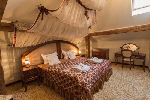 a bedroom with a large bed with a canopy at Dwór Kombornia Hotel&SPA in Kombornia