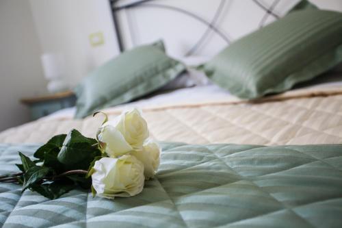 a bouquet of white roses sitting on a bed at Il Portico Camere e Caffè - centro Città in Savignano sul Rubicone