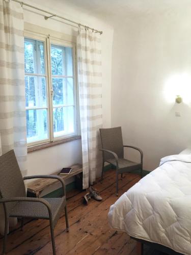 a bedroom with two chairs and a bed and a window at Apartamenti Strand in Saulkrasti