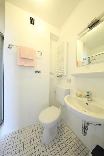 a white bathroom with a toilet and a sink at Hotel Garni Schilling in Duisburg